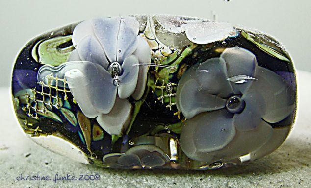 Bunte Glasperle mit blauen und lilafarbenen Blumenmotiven.